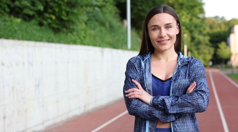 Photo of Happy woman in sportswear at stadium, space for text