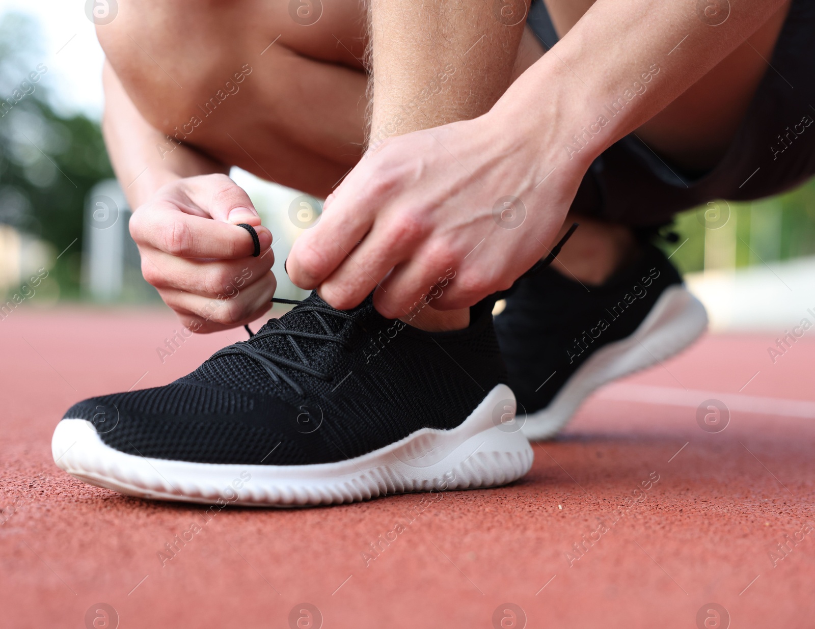 Man tying shoelace of black sneaker at stadium, closeup Photo of Man tying shoelace of black sneaker at stadium, closeup