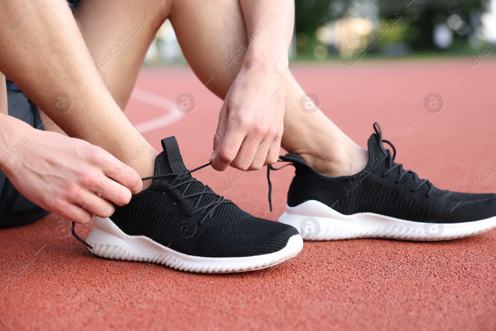 Man tying shoelace of black sneaker at stadium, closeup Photo of Man tying shoelace of black sneaker at stadium, closeup