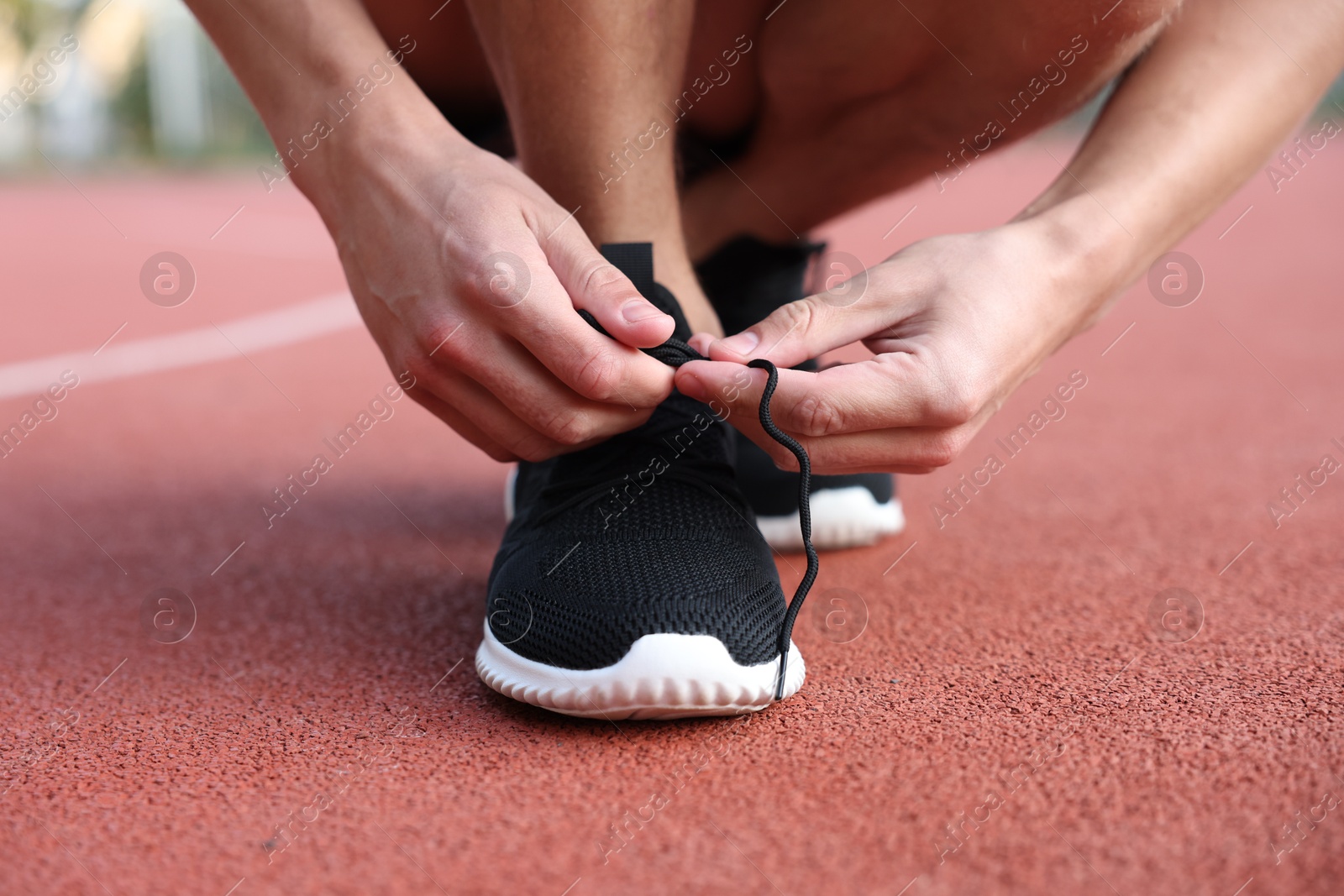 Man tying shoelace of black sneaker at stadium, closeup Photo of Man tying shoelace of black sneaker at stadium, closeup