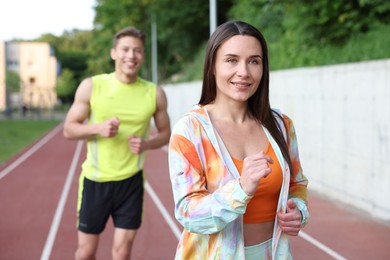 Photo of Sporty couple running at stadium, selective focus