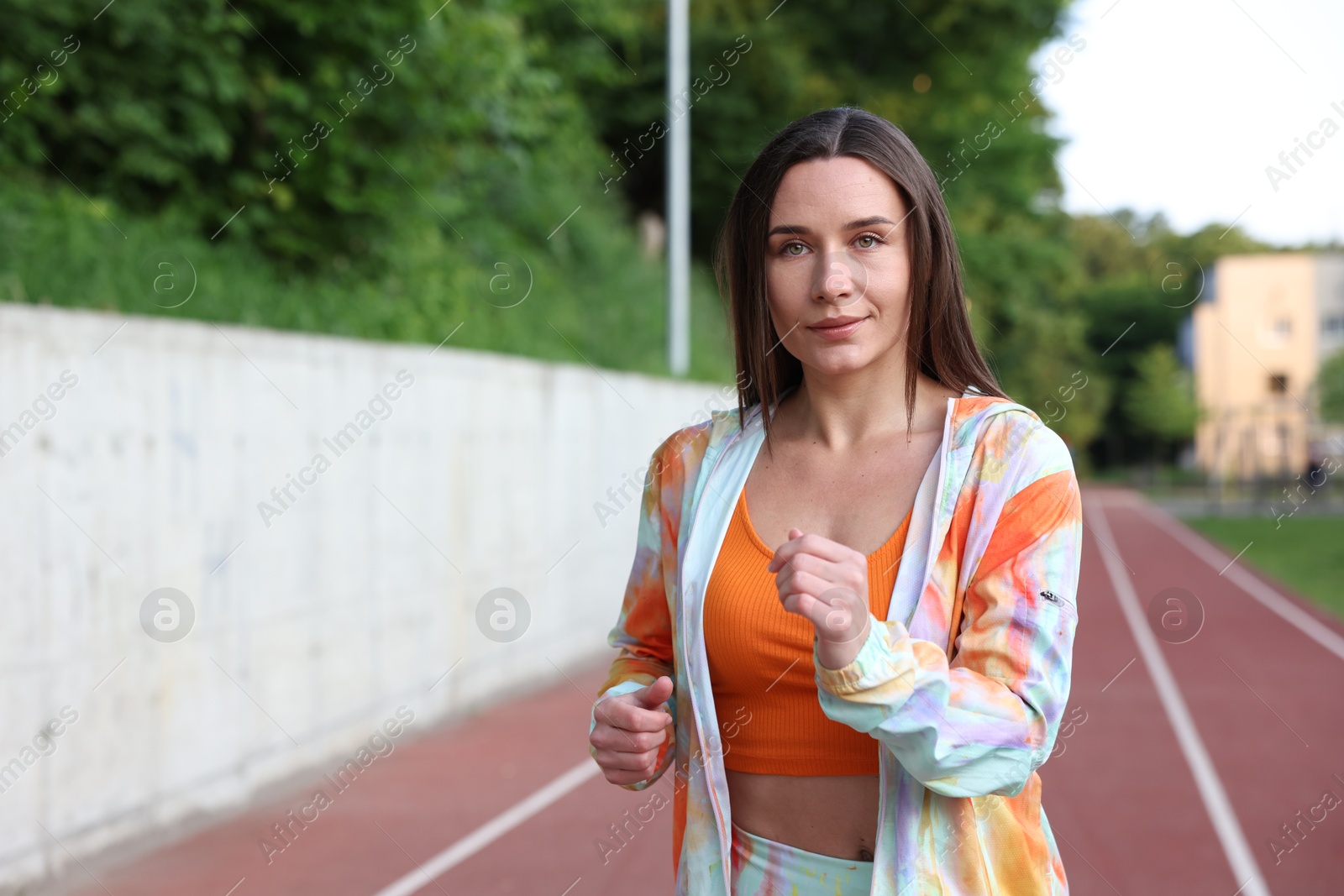 Sporty woman running at stadium, space for text Photo of Sporty woman running at stadium, space for text