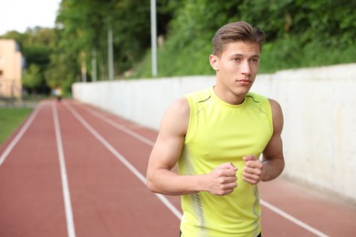 Photo of Sporty man running at stadium, space for text. Healthy lifestyle