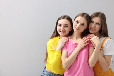 Photo of Friends hugging each other on light grey background, space for text