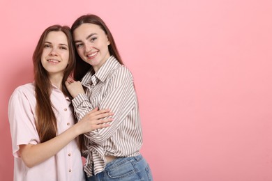Photo of Friends hugging each other on pink background, space for text