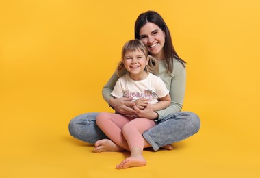 Photo of Happy mother and her cute daughter on orange background