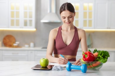 Photo of Woman developing diet plan at white marble table indoors, space for text