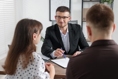 Photo of Couple having meeting with business consultant at table in office