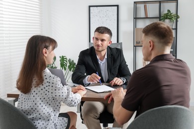 Photo of Couple having meeting with business consultant at table in office