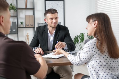 Photo of Couple having meeting with business consultant at table in office