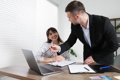 Photo of Consultant working with client at table in office. Business meeting