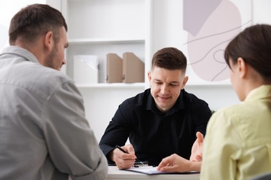 Photo of Couple having meeting with business consultant at table in office