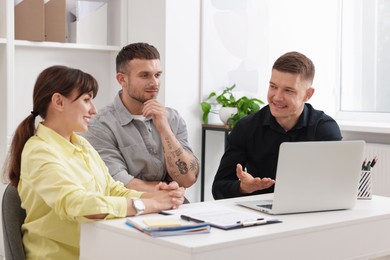 Photo of Couple having meeting with business consultant at table in office