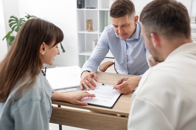 Photo of Couple having meeting with business consultant at table in office