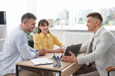 Photo of Couple having meeting with business consultant at table in office