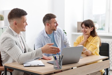 Photo of Couple having meeting with business consultant at table in office