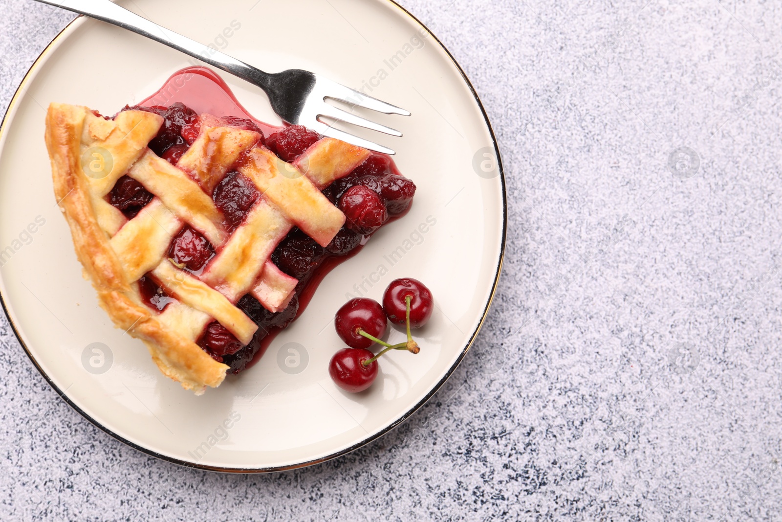 Piece of tasty cherry pie, berries and fork on grey textured table, top view. Space for text Photo of Piece of tasty cherry pie, berries and fork on grey textured table, top view. Space for text