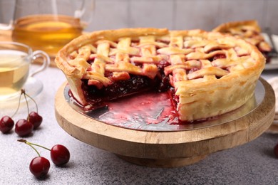 Photo of Tasty cherry pie and berries on grey textured table, closeup