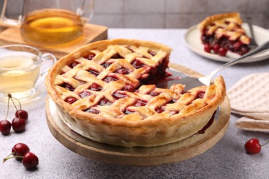 Photo of Tasty cherry pie and berries on grey textured table, closeup