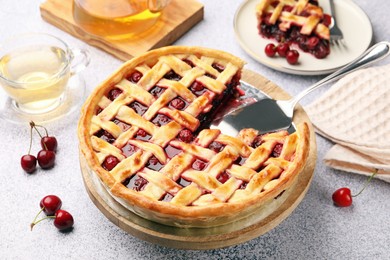 Photo of Tasty cherry pie and berries on grey textured table, closeup