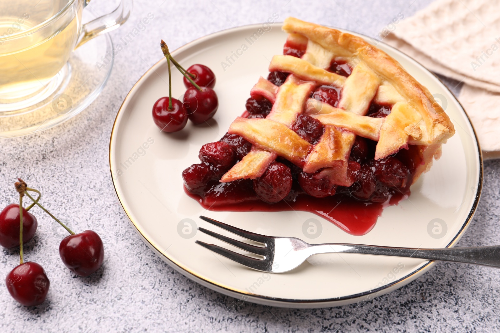 Piece of tasty cherry pie, berries and fork on grey textured table, closeup Photo of Piece of tasty cherry pie, berries and fork on grey textured table, closeup