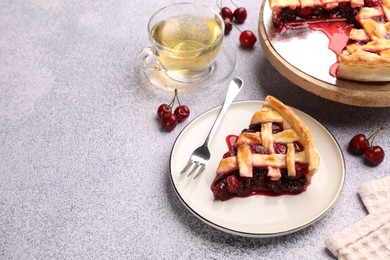Photo of Piece of tasty cherry pie, berries and tea on grey textured table. Space for text