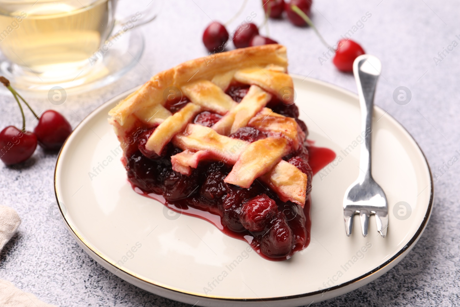 Piece of tasty cherry pie, berries and fork on grey textured table, closeup Photo of Piece of tasty cherry pie, berries and fork on grey textured table, closeup