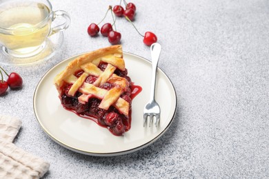 Photo of Piece of tasty cherry pie, berries and tea on grey textured table. Space for text