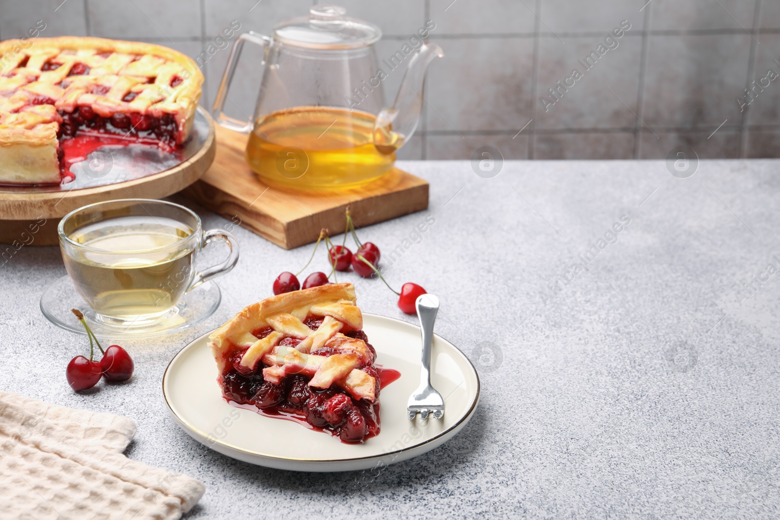 Piece of tasty cherry pie, berries and tea on grey textured table against tiled wall. Space for text Photo of Piece of tasty cherry pie, berries and tea on grey textured table against tiled wall. Space for text