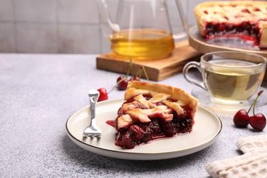 Photo of Piece of tasty cherry pie, berries and tea on grey textured table against tiled wall, closeup