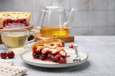 Photo of Piece of tasty cherry pie, berries and tea on grey textured table against tiled wall, closeup