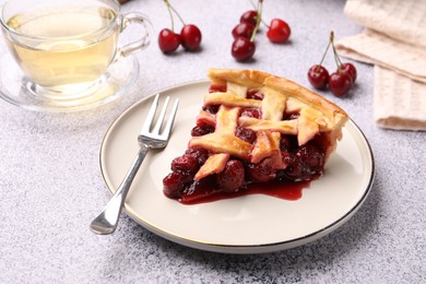 Photo of Piece of tasty cherry pie, berries and tea on grey textured table, closeup