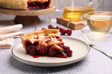Photo of Piece of tasty cherry pie on grey textured table, closeup