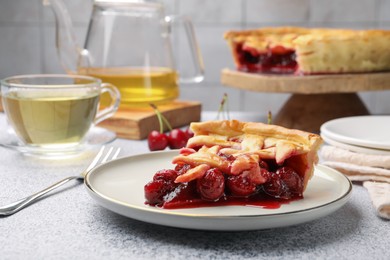 Photo of Piece of tasty cherry pie on grey textured table, closeup