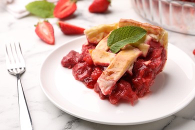 Photo of Piece of tasty strawberry pie and fork on white marble table, closeup