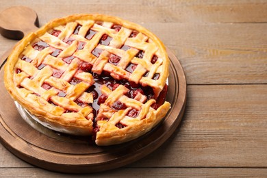 Photo of Tasty cut cherry pie on wooden table, closeup. Space for text