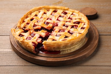 Photo of Tasty cut cherry pie on wooden table, closeup