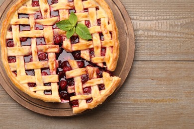 Photo of Tasty cut cherry pie on wooden table, top view. Space for text