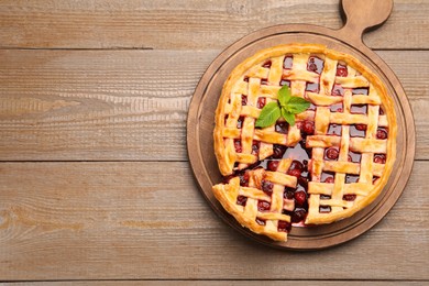 Photo of Tasty cut cherry pie on wooden table, top view. Space for text