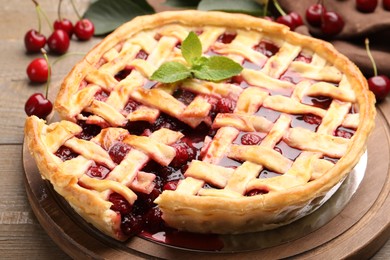 Photo of Tasty cut cherry pie and berries on wooden table, closeup