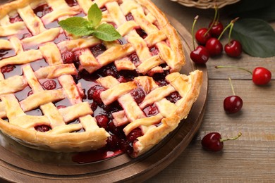 Photo of Tasty cut cherry pie and berries on wooden table, closeup