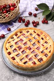 Photo of Tasty cherry pie and berries on grey textured table, closeup