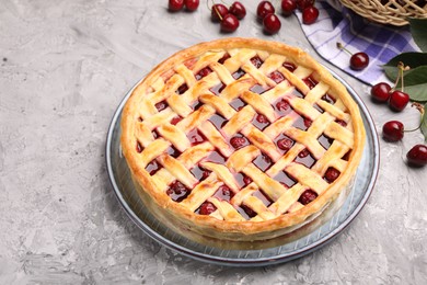 Photo of Tasty cherry pie and berries on grey textured table, closeup