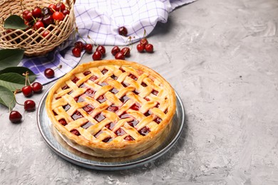 Photo of Tasty cherry pie and berries on grey textured table. Space for text