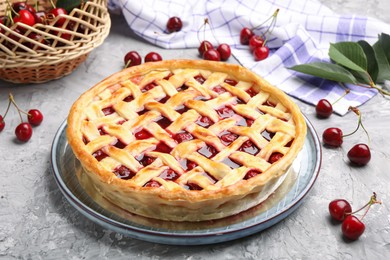Photo of Tasty cherry pie and berries on grey textured table, closeup