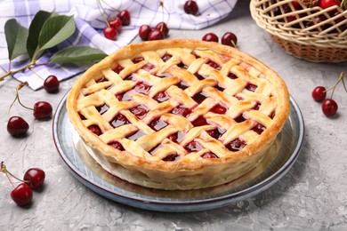 Photo of Tasty cherry pie and berries on grey textured table, closeup