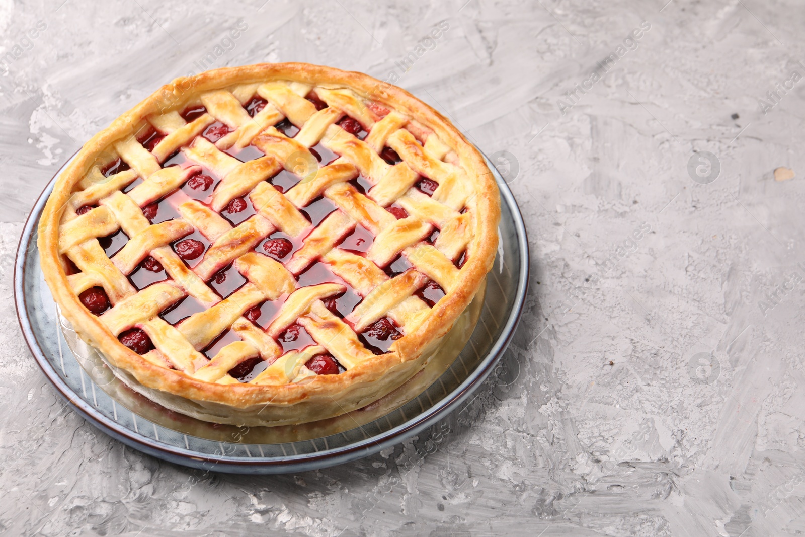 Photo of Tasty cherry pie on grey textured table, closeup. Space for text