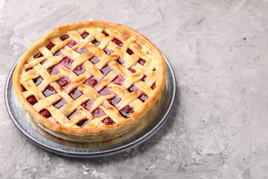 Photo of Tasty cherry pie on grey textured table, closeup. Space for text