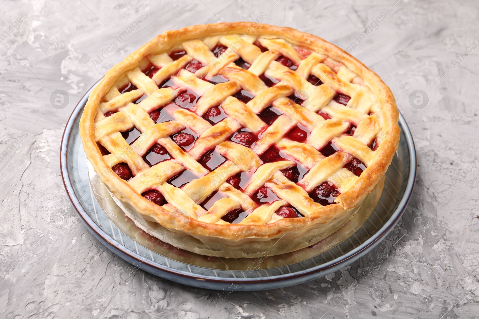 Photo of Tasty cherry pie on grey textured table, closeup