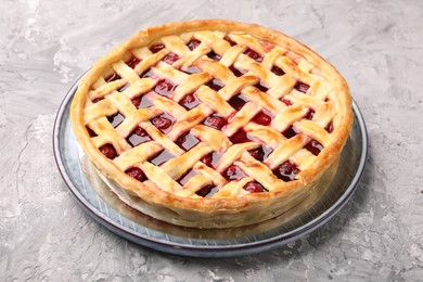Photo of Tasty cherry pie on grey textured table, closeup
